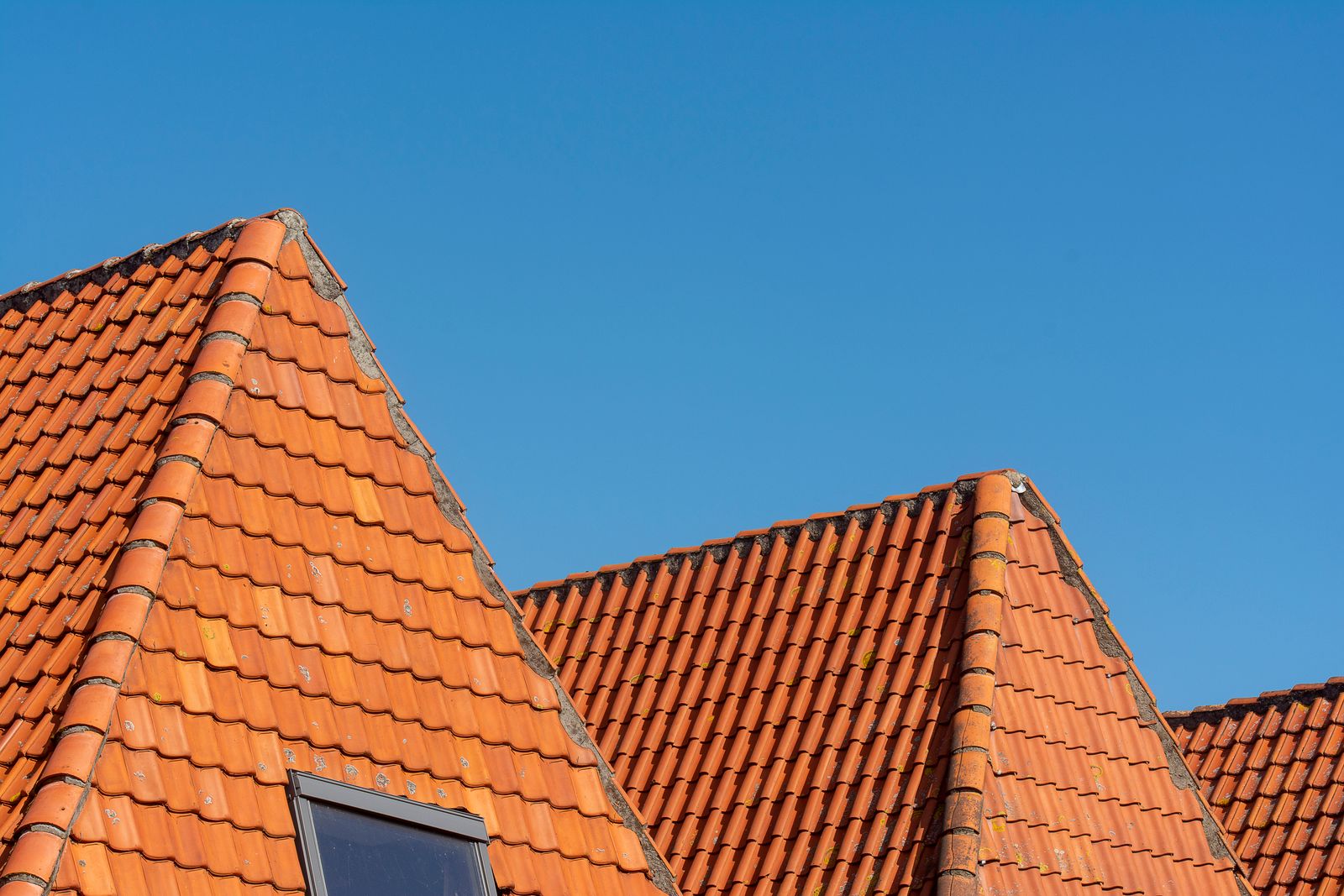 Clay tiled roof gable on a British home against a blue sky